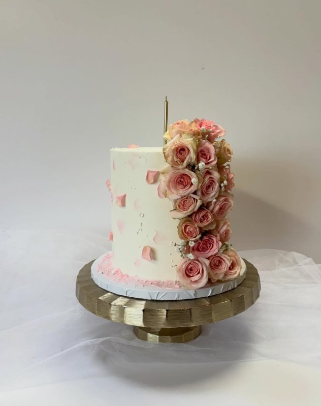 Classic white wedding cake with cascading pink roses on a gold stand