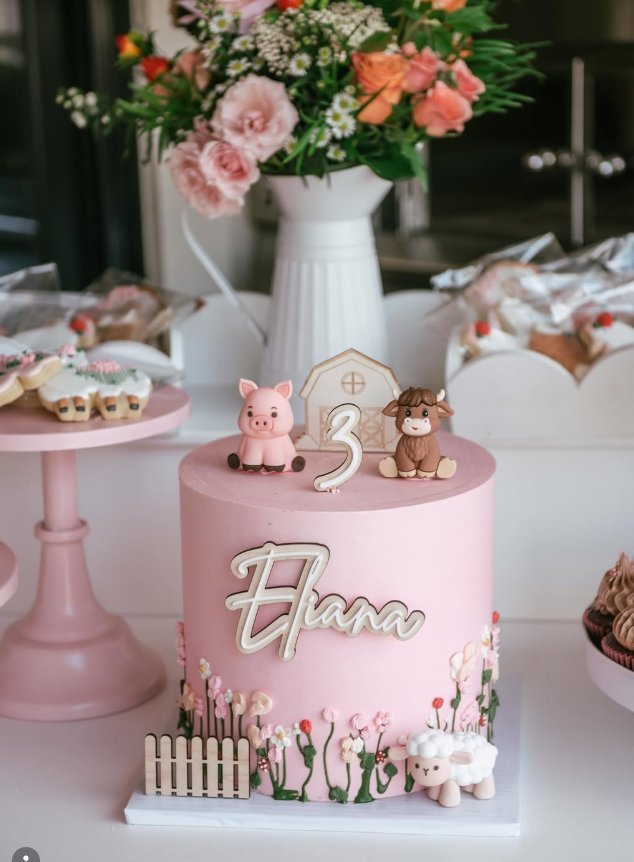 Pink themed birthday celebration cake with custom fondant details and floral arrangement